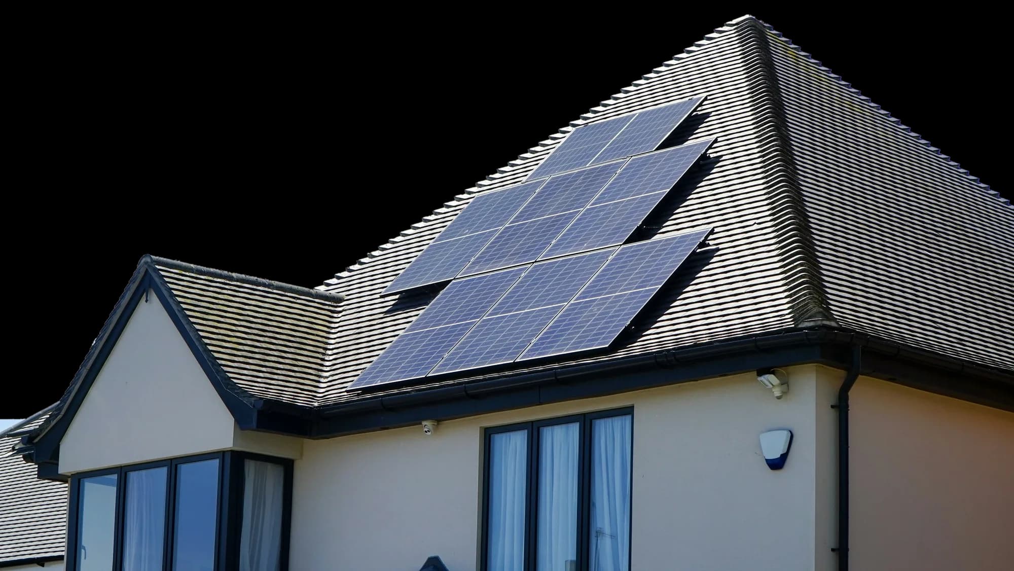 A two-storey home with a twelve-panel solar array on its tiled roof, under a clear sky